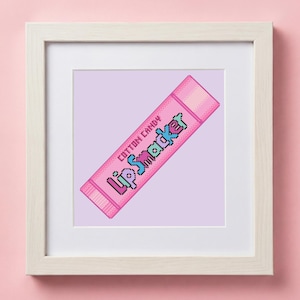 May include: A framed print showing a pink pixelated design of a Lip Smacker cotton candy lip balm tube. The text "Cotton Candy" and "Lip Smacker" are visible. The background is a light purple colour.