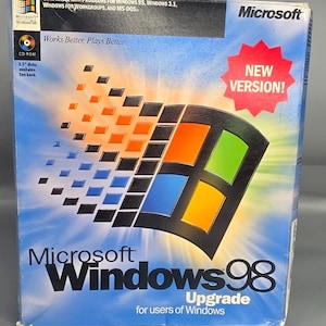 Puede incluir: Una caja de software Microsoft Windows 98 Upgrade con el icónico logotipo de ventana de cuatro colores sobre un fondo azul. La caja incluye el texto New Version, Works Better, Plays Better y detalles de compatibilidad para Windows 95 y 3.1.