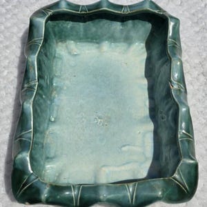 May include: A rectangular ceramic planter with a glossy, deep teal glaze. The exterior features a textured, bamboo-like design with vertical ridges along the rim. The interior is a lighter, pale blue-green shade with a smooth, glazed finish.