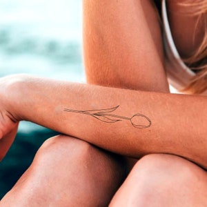 May include: A simple line drawing of a tulip flower on a person's arm.