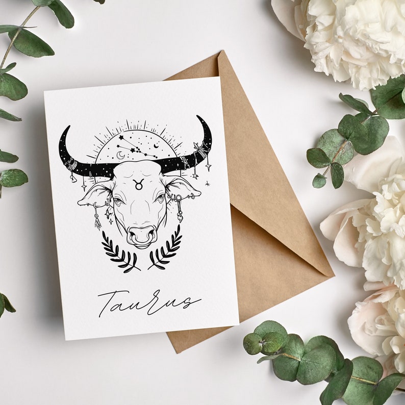 May include: A black and white illustration of a Taurus zodiac sign with a bull's head surrounded by stars and a crescent moon. The text "Taurus" is written below the illustration.