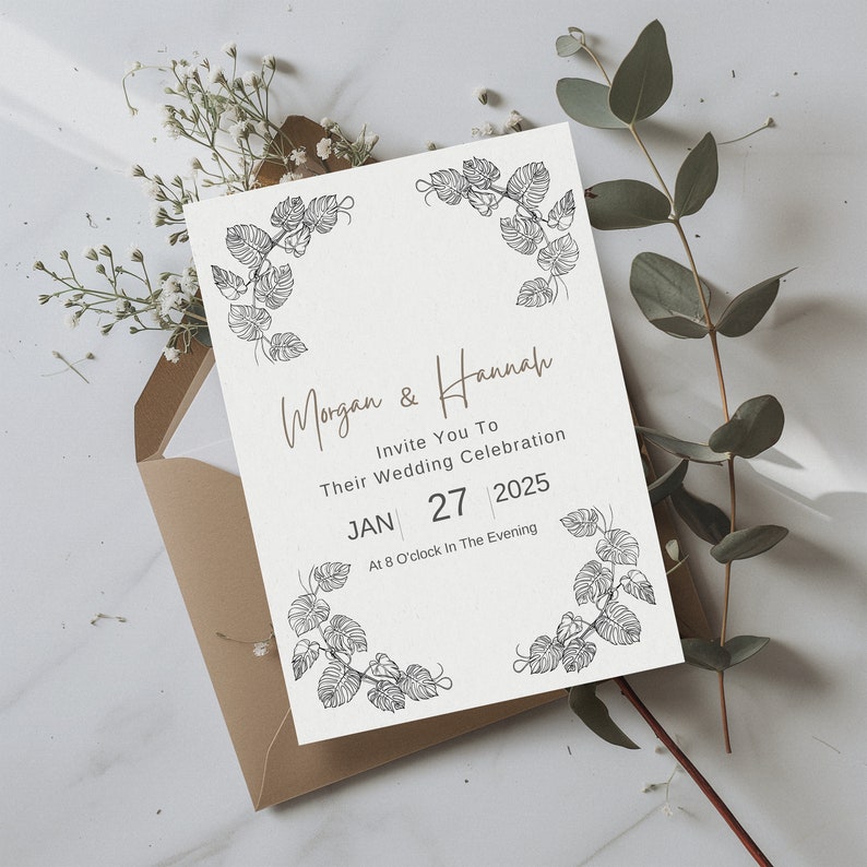 K&ouml;nnte beinhalten: Eine wei&szlig;e Hochzeitseinladung mit floralem Rand. Die Einladung lautet "Morgan & Hannah Invite You To Their Wedding Celebration JAN 27 2025 At 8 O'clock In The Evening".