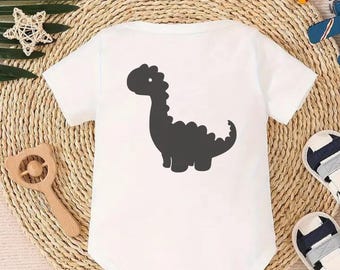 Könnte beinhalten: Weißer Baby-Strampler mit einer schwarzen Silhouette eines Dinosauriers auf der Rückseite.