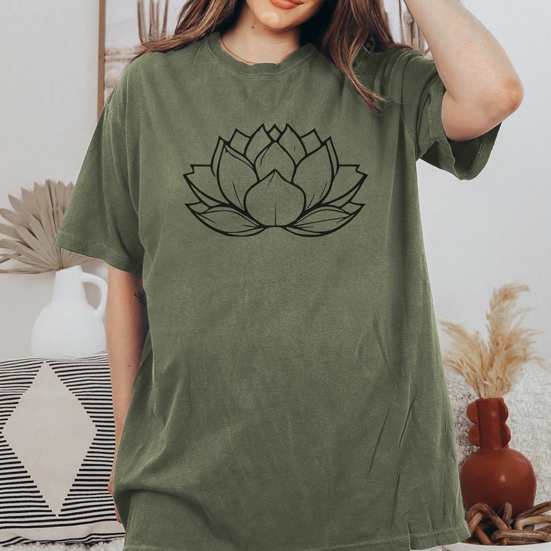 May include: A green t-shirt with a black outline of a lotus flower on the front.