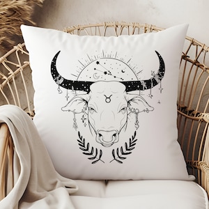 May include: White pillow with a black line drawing of a bull's head with a star and crescent moon design above it. The bull has a Taurus symbol on its forehead and is adorned with celestial-themed jewelry.