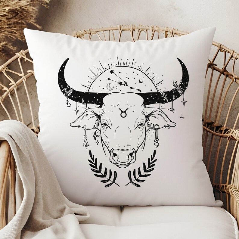 May include: White pillow with a black line drawing of a bull's head with a star and crescent moon design above it. The bull has a Taurus symbol on its forehead and is adorned with celestial-themed jewelry.