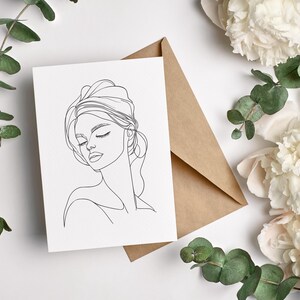 May include: A black and white line drawing of a woman's face with her eyes closed. The drawing is on a white card.