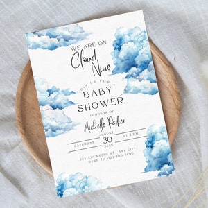 Puede incluir: Una invitación a una baby shower con un diseño de acuarela de nubes azules. El texto dice "We are on Cloud Nine. Join us for a Baby Shower in honor of Michelle Parker. Saturday, August 30, 2025 at 4 PM. 123 Anywhere St. Any City. RSVP to 123-456-7800."