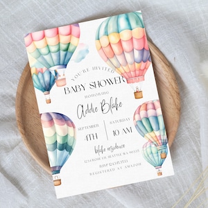 May include: A baby shower invitation with a watercolor illustration of hot air balloons in shades of pink, blue, and yellow. The text reads "You're Invited Baby Shower Honoring Addie Blake September 4th Saturday 10 AM Blake Residence 1234 Rose Ln, Seattle WA 90335 RSVP 24363533 Registered at Amazon"