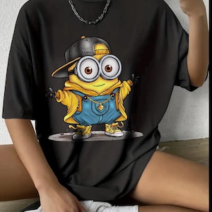 May include: Black oversized t-shirt with a cartoon image of a minion wearing a backwards baseball cap that says "Brand Original" and blue overalls.