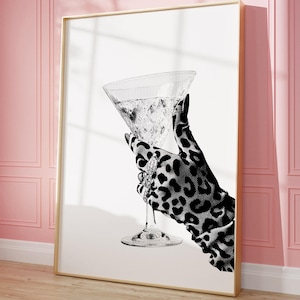 以下が含まれることがあります： ヒョウ柄の手袋をした手が、マティーニグラスを持っている、白黒のイラストです。