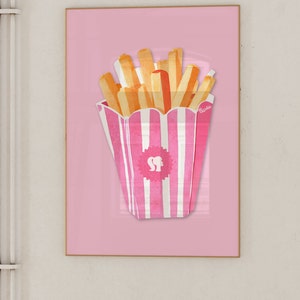 May include: A framed print featuring a pink and white striped container of french fries against a pink background. The fries are yellow and orange. The container has a logo with a silhouette of a woman's head and the word "Barbie".