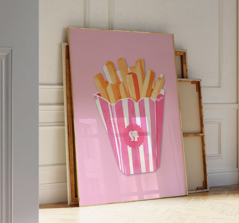 May include: A pink and white striped container filled with watercolor-style french fries. The fries are shades of orange and yellow. The artwork is framed in gold and set against a pink background. The container has a pink logo with a silhouette of a woman's head.