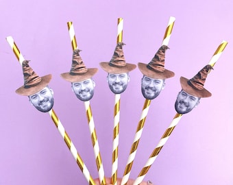 May include: Five gold and white striped paper straws with a photo of a person's face wearing a brown wizard hat attached to each straw.