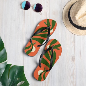 Japonki Tropical Twist w kolorze pomarańczowym i zielonym, o nowoczesnym, roślinnym designie. Idealne na lato. Komfort i styl inspirowane tropikami.
