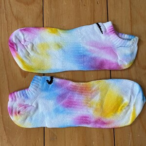 May include: Two pairs of colorful tie-dye socks with a white background and blue, yellow, and pink accents. The socks are made of a soft, breathable fabric and are perfect for everyday wear.