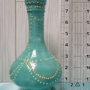 K&ouml;nnte beinhalten: Eine t&uuml;rkisfarbene Keramikvase mit bauchigem Boden und schlankem Hals. Die Vase ist mit kleinen, erhabenen orangefarbenen und gelben Punkten verziert. Die Vase ist etwa 20 cm hoch.