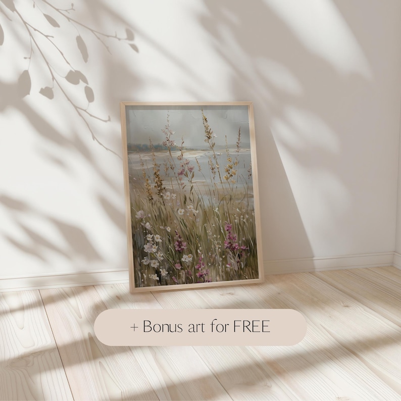 May include: A framed landscape art print featuring a field of wildflowers in shades of pink, yellow, and white, with a body of water in the background. The artwork is in a light wooden frame. Text at the bottom reads '+ Bonus art for FREE'.