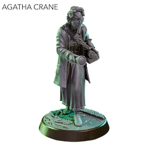 Puede incluir: Figura gris de una persona con parche en el ojo, sosteniendo un dispositivo y una linterna. La figura está sobre una base redonda con un diseño detallado. El texto "AGATHA CRANE" está en la parte superior.