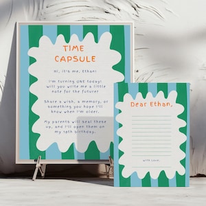 Puede incluir: Una impresión enmarcada y una tarjeta con el tema de la cápsula del tiempo. La impresión tiene un borde blanco ondulado con rayas verdes y azules. El texto en la impresión dice "TIME CAPSULE" e incluye un mensaje para escribir una nota para el futuro. La tarjeta dice "Dear Ethan."