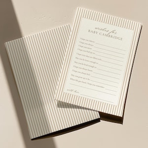 May include: Two beige and white striped baby shower cards. The top card reads "wishes for BABY CAMBRIDGE" with lines for guests to write on. The bottom card is closed, showing the striped pattern.