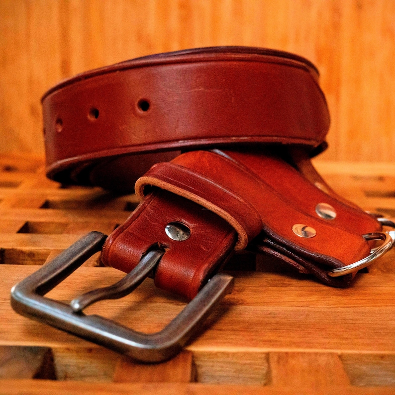 May include: A brown leather belt with a silver buckle. The belt is folded in half and the buckle is visible.