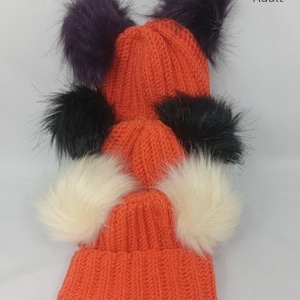 Puede incluir: Gorros de ganchillo naranja con pompones de piel sintética en morado, negro y crema. Los gorros están apilados, mostrando diferentes tallas para 0-3 meses, 3-6 meses, 6-9 meses y adulto. El texto en la imagen dice "Super Easy Linked Single Crochet Hat."