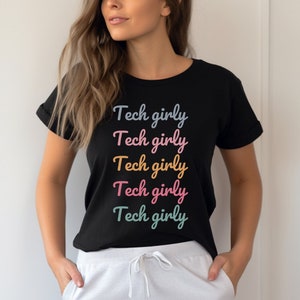 May include: Black t-shirt with the text "Tech girly" repeated in rainbow colors.