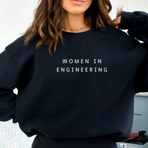 May include: Black sweatshirt with the text "Women in Engineering" printed in white on the front.