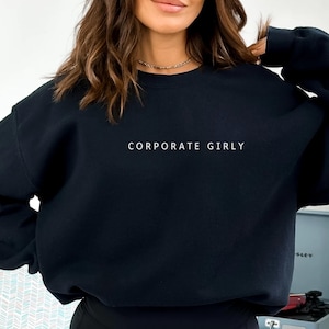 May include: Black sweatshirt with the text "CORPORATE GIRLY" in white.