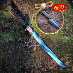 May include: A blue and silver katana sword with a black handle and a gold accent. The sword is lying on a green and brown surface. FREE! is written on a red banner.