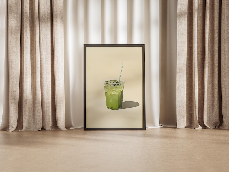 May include: A framed print of a green iced drink with a straw in a clear plastic cup. The drink is on a light beige background.