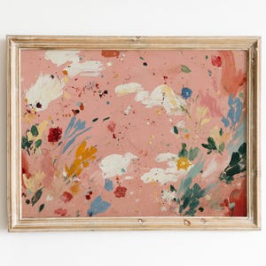 May include: Abstract art print in a wooden frame. The artwork features a pink background with colorful paint splatters and brushstrokes in white, red, yellow, and blue. The framed art is a decorative piece.