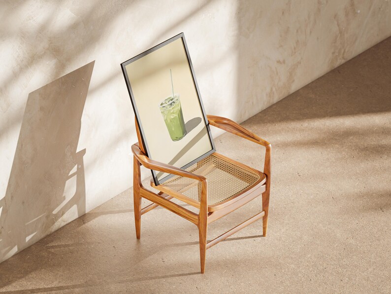 May include: A framed print of a green iced drink with a straw, sitting on a wooden chair with a woven cane seat.