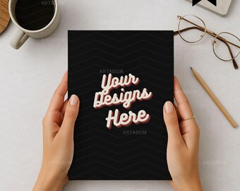 May include: A black notebook with a chevron pattern is held by a person. The text "Your Designs Here" is displayed in a retro font. A gold bracelet and ring are visible. A cup of coffee, glasses, and a pencil are on the table.