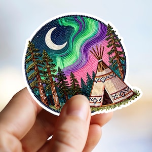 May include: A round sticker featuring a beaded design of a night scene. The image includes a crescent moon, aurora borealis, pine trees, and a teepee. The color palette includes shades of green, purple, pink, and blue.