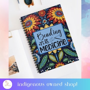 May include: A spiral bound notebook with a colorful beaded floral design. The cover features a blue rectangle with the text "Beading is Medicine" in white lettering.