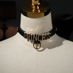 Collar gargantilla de cuero negro con letras personalizadas y correa, ideal como regalo romántico para el día del nombre.