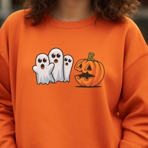 Può includere: Felpa arancione con grafica a tema Halloween. Il design include tre fantasmi bianchi dei cartoni animati e una zucca intagliata. La felpa è di colore arancione pieno, perfetta per la stagione autunnale.