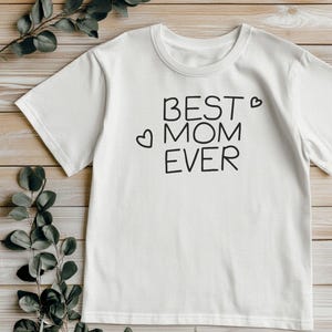 May include: White t-shirt with the text "Best Mom Ever" in black lettering and two small hearts.