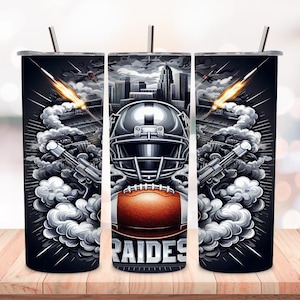 May include: A black and white tumbler with a football helmet, football, and the word "RAIDERS" on it. The background is a cityscape with smoke and jets flying overhead.