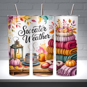 Può includere: Tre bicchieri isolati in acciaio inossidabile con la scritta "Sweater Weather" stampata. I bicchieri presentano illustrazioni a tema autunnale, tra cui zucche, candele e pile di maglioni nei toni dell'arancione, del rosa e del verde acqua.