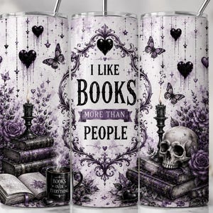 Op de afbeelding: Een cilindrische beker met een paars en wit ontwerp met de tekst I LIKE BOOKS MORE THAN PEOPLE. De afbeelding bevat stapels boeken, een menselijke schedel, brandende kaarsen, vlinders en hangende zwarte harten tegen een florale achtergrond.