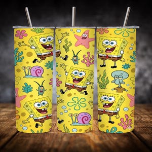 Op de afbeelding: Drie gele geïsoleerde bekers met roestvrijstalen rietjes. Elke beker heeft een herhaald patroon van SpongeBob SquarePants en andere personages uit de animatieserie, met een gele achtergrond.