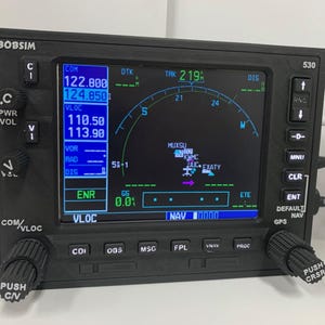 May include: Black electronic flight instrument panel with a screen displaying flight data, including navigation information and a map. The panel has multiple buttons, knobs, and the text "BOBSIM" at the top.
