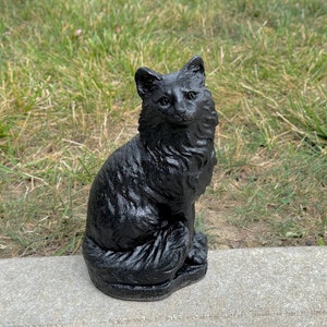 Peut inclure: Une figurine de chat en c&eacute;ramique noire avec une queue touffue et une pose assise. Le chat a une apparence r&eacute;aliste avec une fourrure et des traits du visage d&eacute;taill&eacute;s.
