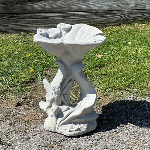 K&ouml;nnte beinhalten: Ein wei&szlig;er Vogelbad aus Beton mit einer Feenskulptur auf der Basis. Das Vogelbad ist blumenf&ouml;rmig mit einer breiten, flachen Schale.