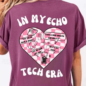 Puede incluir: Una camiseta morada con un gráfico de corazón rosa que dice "In My Echo Tech Era". El gráfico del corazón tiene un patrón a cuadros e incluye texto como "Yes you do have a heart", "Take a deep breath and hold it", "Lay on your left side", y "No it's not twins".