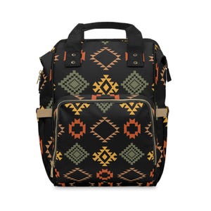 May include: Black backpack with a geometric pattern in orange, yellow, and green. The bag has a top handle, two shoulder straps, and multiple pockets. The design features diamond and square shapes.