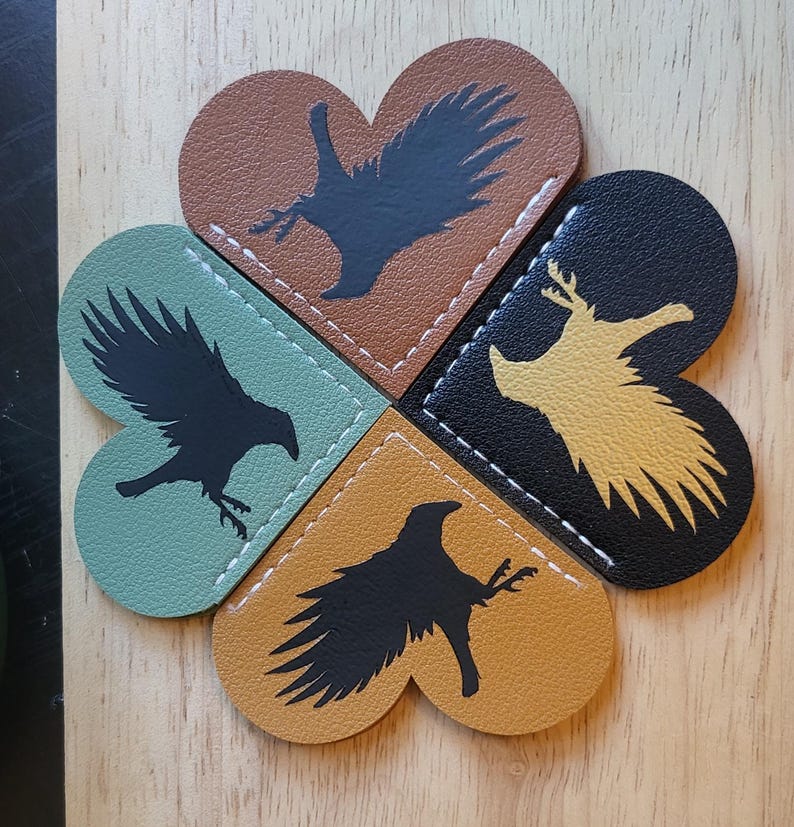 May include: Four heart-shaped leather bookmarks with different colored backgrounds and black silhouettes of birds. The bookmarks are sewn together to form a clover shape.
